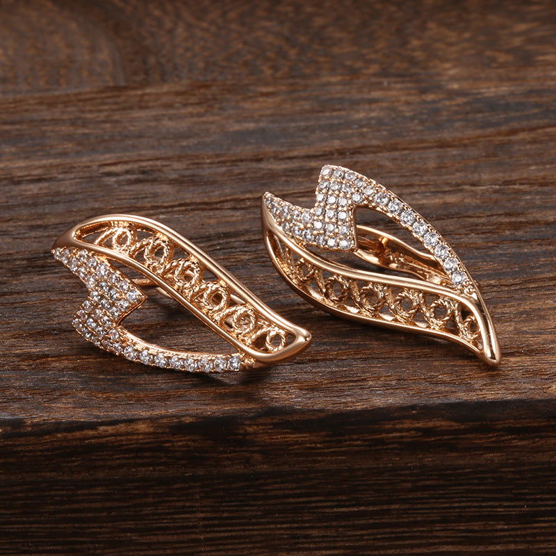 Pair of gold earrings with diamond accents on a wooden surface